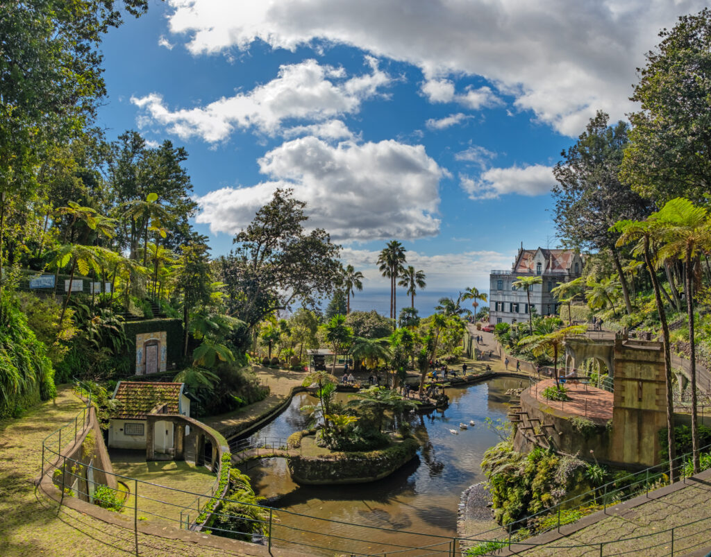 A picturesque Monte Palace tropical garden in Funchal on Madeira. Reflective pond surrounded by lush, vibrant greenery and architectural structures